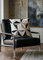 Black and ivory faceted cowhide cushion styled on a black leather armchair