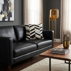Black and white chevron cowhide cushion styled on a black leather sofa in a contemporary interior