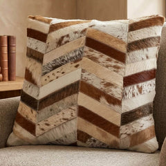 Brown and ivory chevron cowhide cushion styled on a neutral armchair in a warm contemporary interior