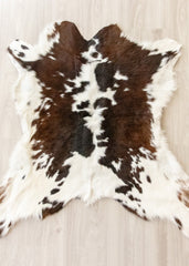Brown and white calfskin hide rug on a light wooden floor