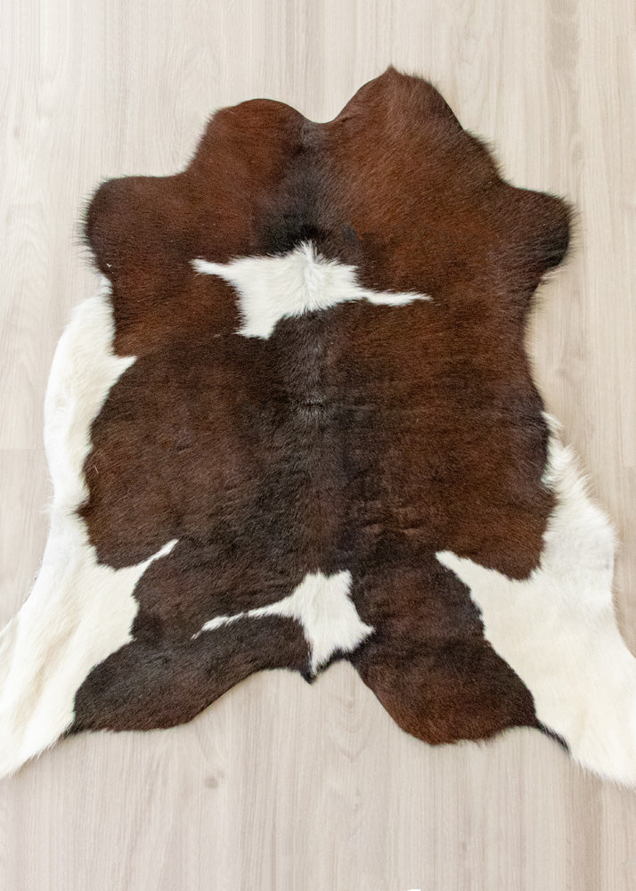 Brown and white calfskin hide rug on a wooden floor