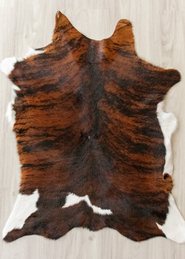 Brown and black calfskin hide rug on a light wooden floor