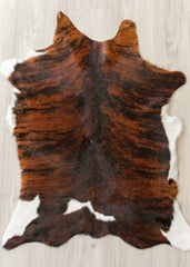 Brown and black calfskin hide rug on a light wooden floor