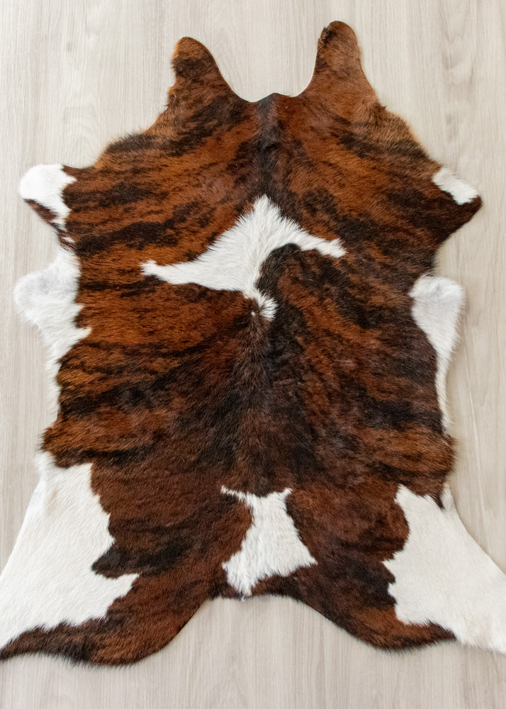 Brown and white calfskin hide rug on a wooden floor