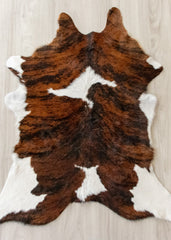 Brown and white calfskin hide rug on a wooden floor
