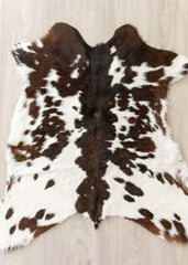 Brown and white calfskin hide rug on a light wooden floor