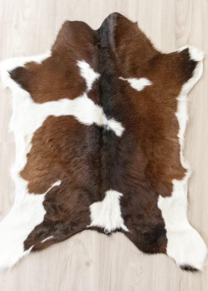 Brown and white calfskin hide rug on a wooden floor