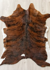 Brown and black calfskin hide rug on a light wooden floor