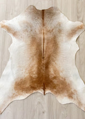 Brown and white calfskin rug on a wooden floor