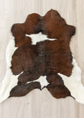 Brown and white calfskin hide rug on a wooden floor