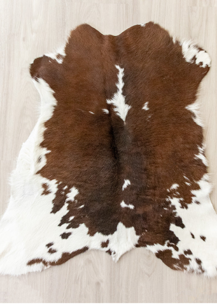 Brown and white calfskin hide rug on a light wooden floor