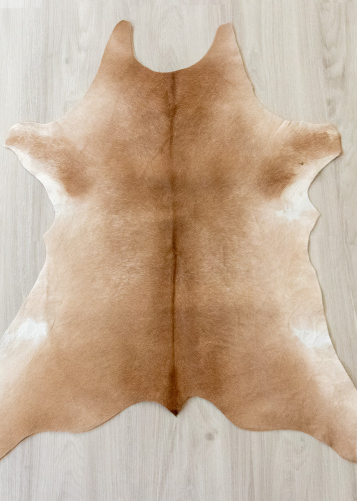 Brown calfskin hide rug on a light wooden floor