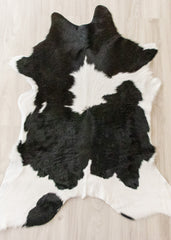 Black and white calfskin hide rug on a wooden floor