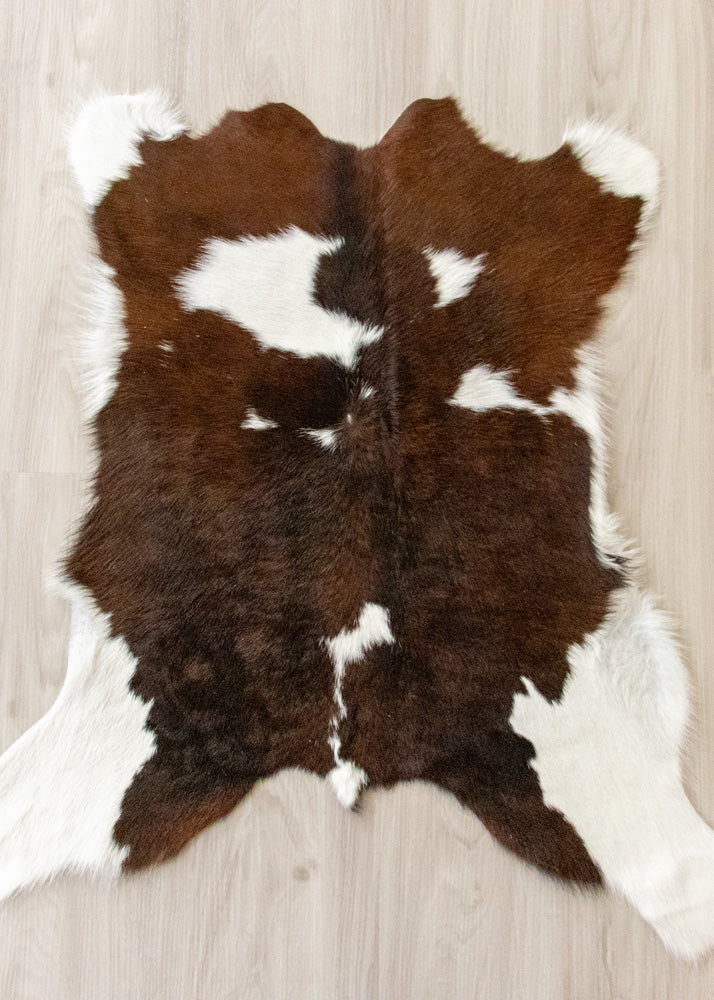 Brown and white calfskin hide rug on a wooden floor