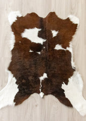 Brown and white calfskin hide rug on a wooden floor