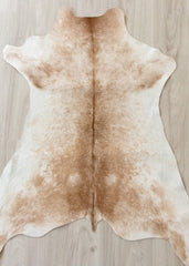 calfskin brown and white rug on a wooden floor