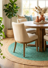 Dining room with a wooden table, beige chairs, and a teal jute round rug.