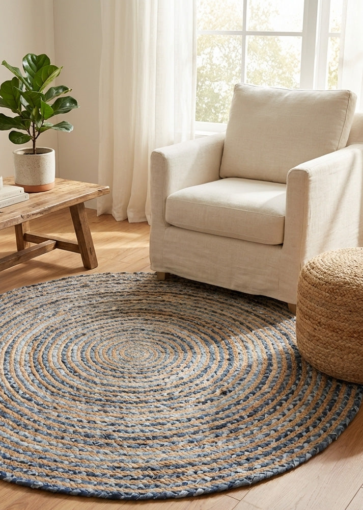 Round braided jute rug in a living room with a beige armchair and wooden coffee table.