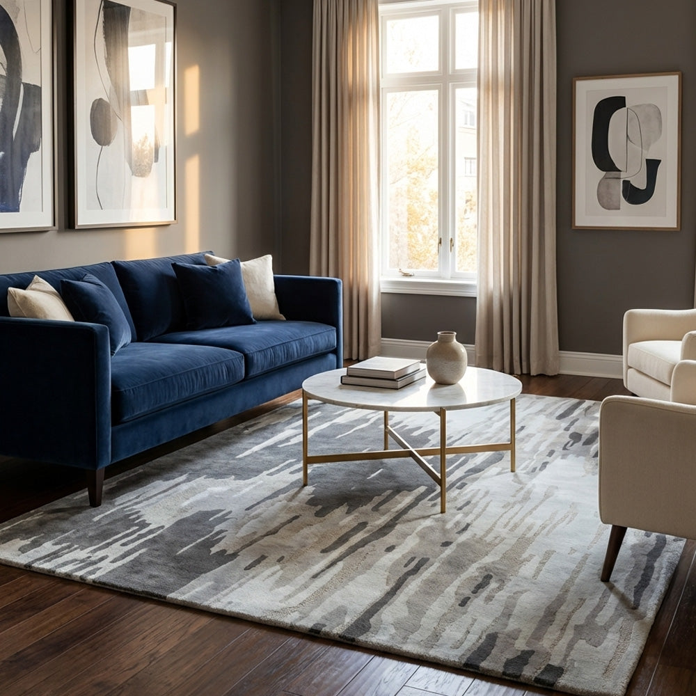 Modern living room with a blue sofa, coffee table, and abstract art on a gray rug.
