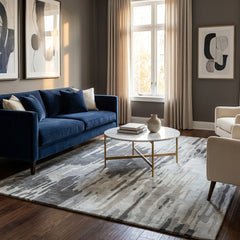 Modern living room with a blue sofa, coffee table, and abstract art on a gray rug.