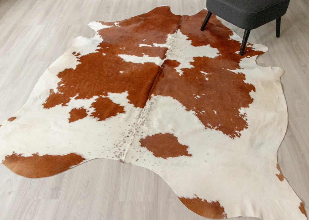 Brown and white cowhide rug on a wooden floor