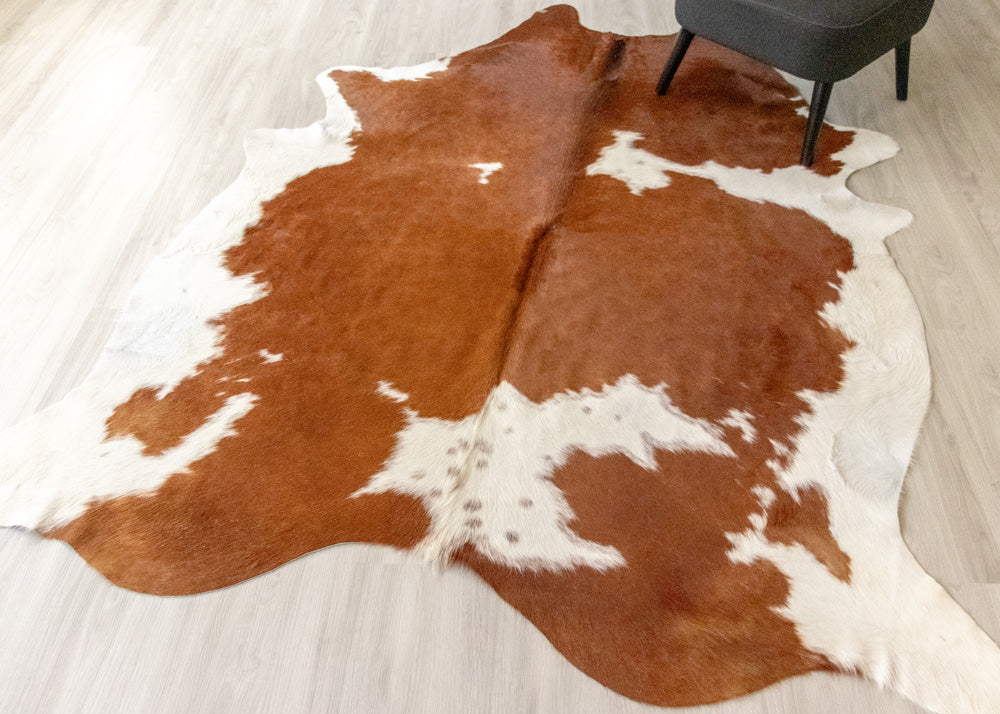 Brown and white cowhide rug on a light wooden floor.