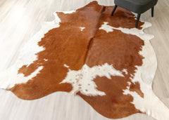 Brown and white cowhide rug on a light wooden floor.
