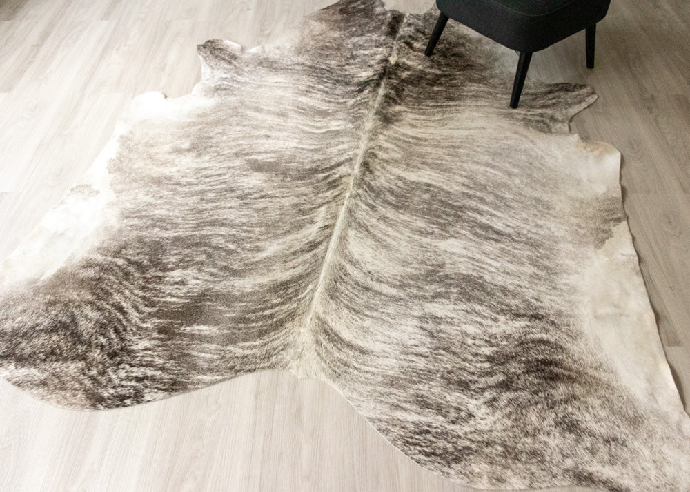 Grey and white brindle cowhide rug on a wooden floor