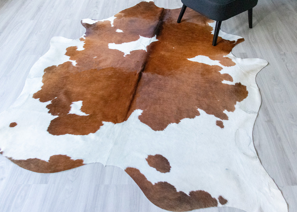 Brown and white cowhide rug on a wooden floor
