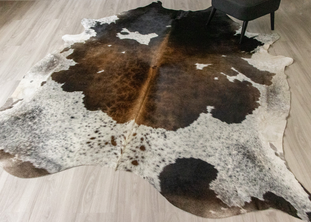 Mettalic brown and white cowhide rug on a wooden floor