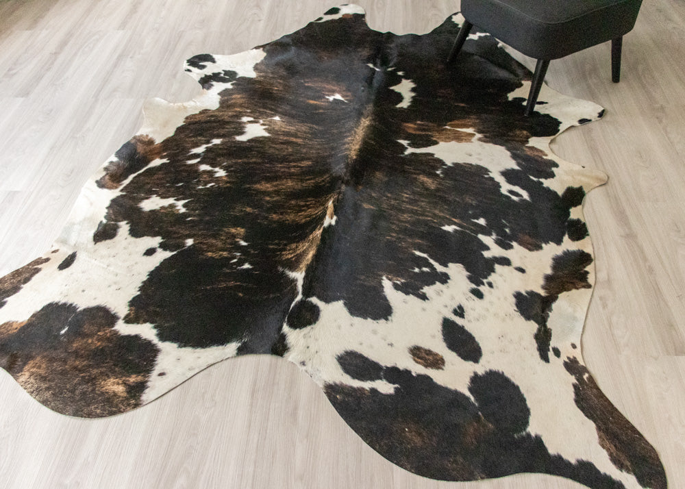 Cowhide rug with black and white brindle on a wooden floor