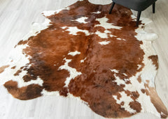 Brown and white brindle cowhide rug on a light wooden floor.