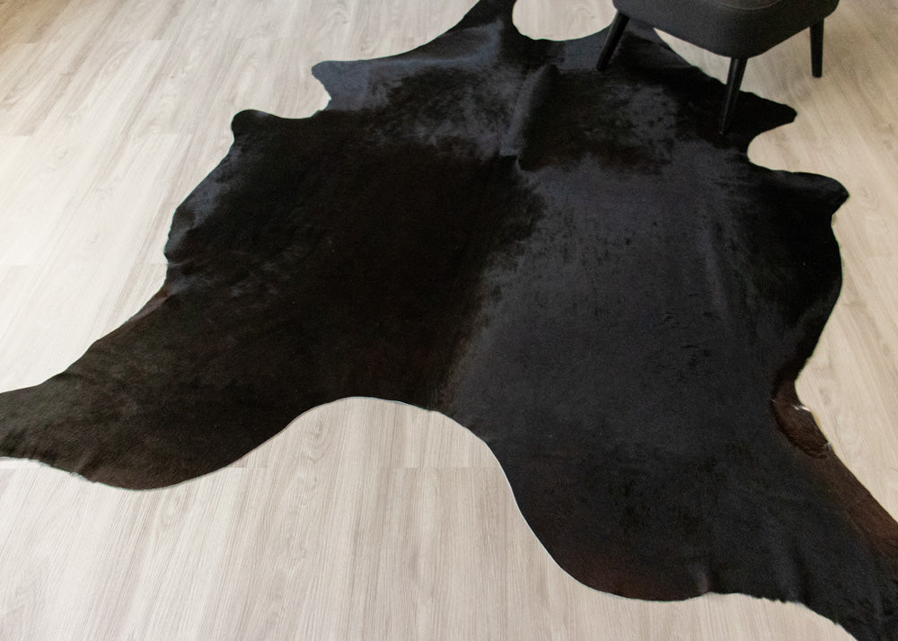 Black cowhide rug on a light wooden floor