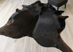 Black cowhide rug on a light wooden floor