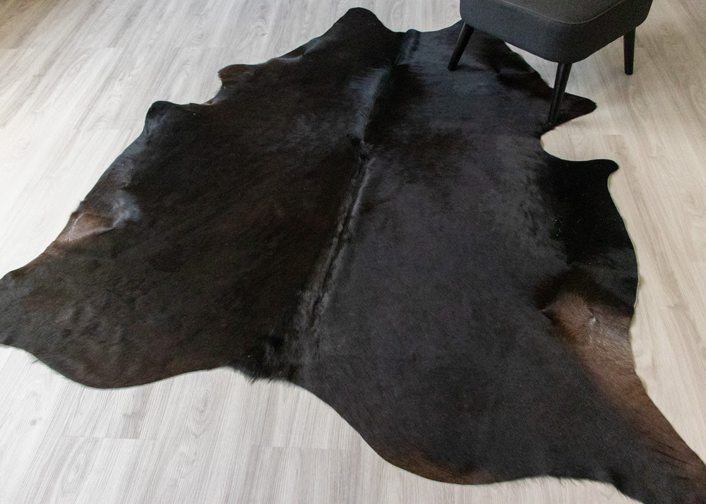 Black cowhide rug on a light wooden floor