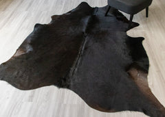 Black cowhide rug on a light wooden floor