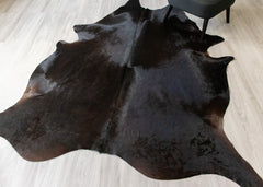 Black cowhide rug on a light wooden floor