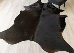 black cowhide rug on a light wooden floor
