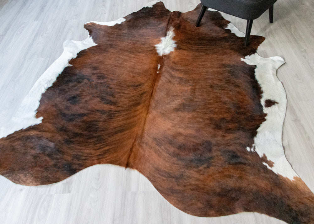 Brown and white brindle cowhide rug on a light wooden floor