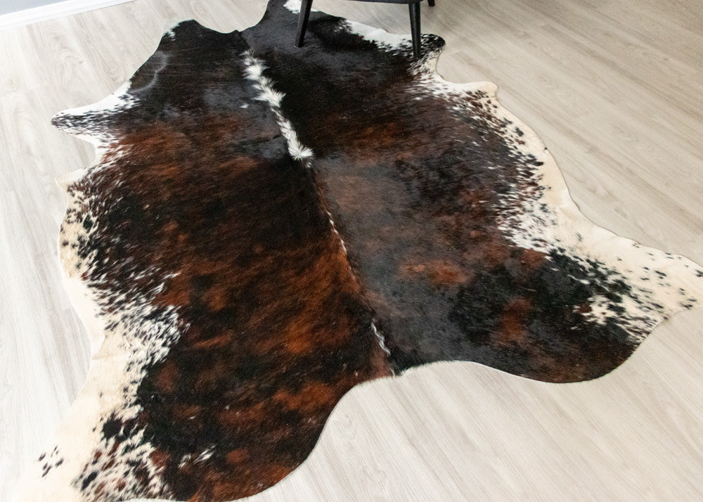 Brown and black cowhide rug on a light wooden floor