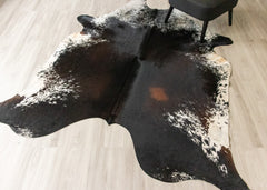 Black and white cowhide rug on a wooden floor