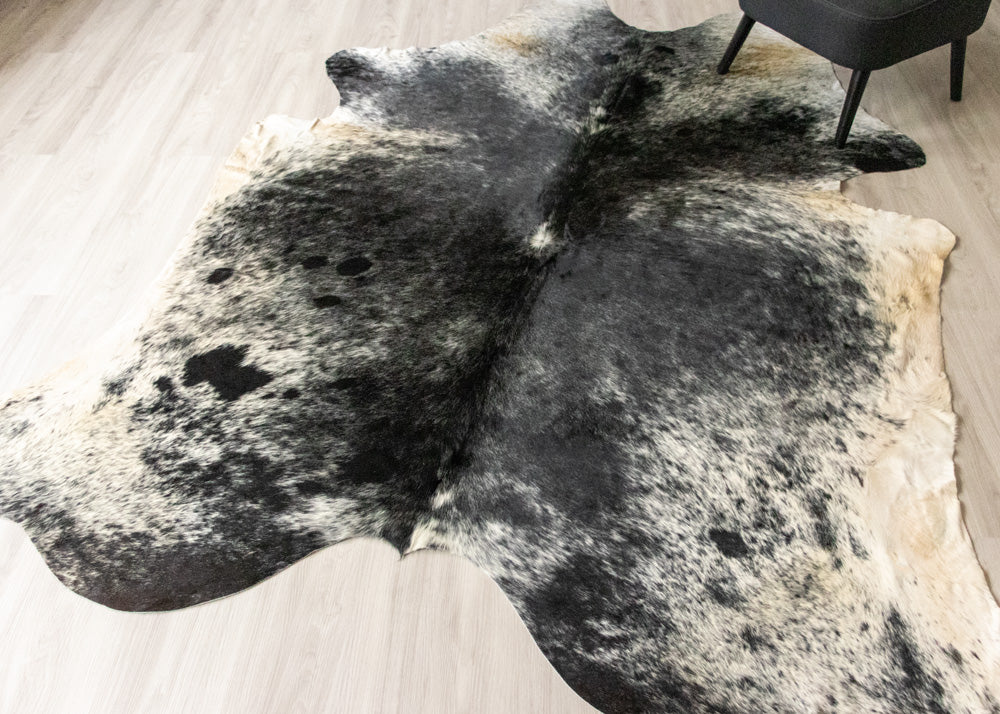 Black and white cowhide rug on a wooden floor