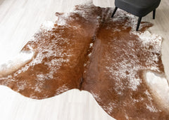 Brown and white cowhide rug on a light wooden floor
