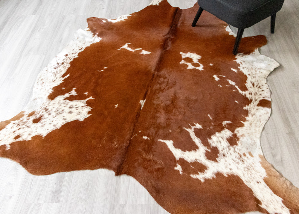 Brown and white cowhide rug on a light wooden floor.
