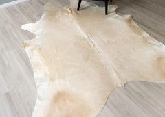 Beige champagne cowhide rug on a wooden floor