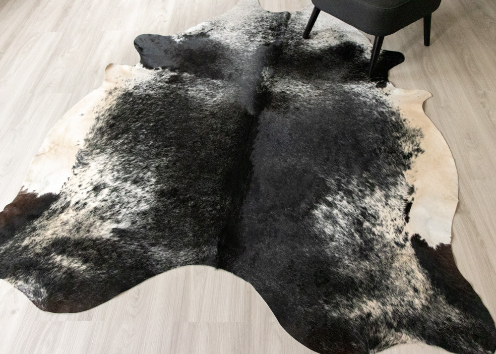 Black and white cowhide rug on a wooden floor