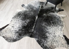 Black and white salt peppar cowhide rug on a wooden floor