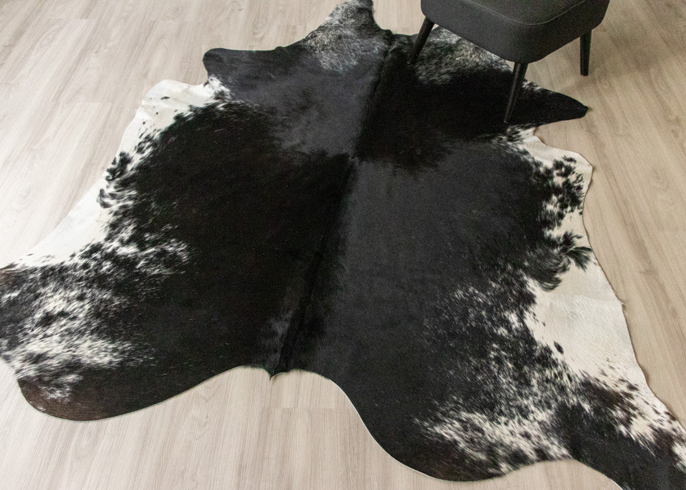Black and white cowhide rug on a wooden floor