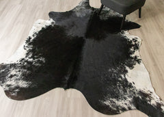 Black and white cowhide rug on a wooden floor