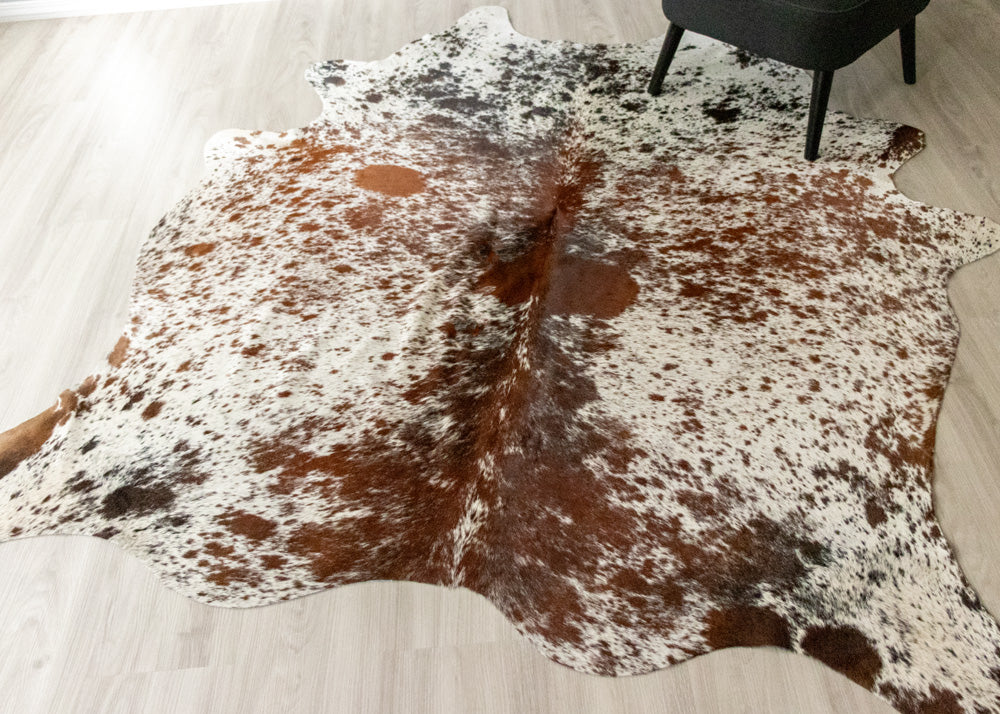 Cowhide rug with brown and white pattern on a light wooden floor.